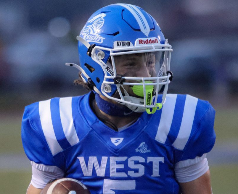 A football player with a helmet on smiles through his mouth guard